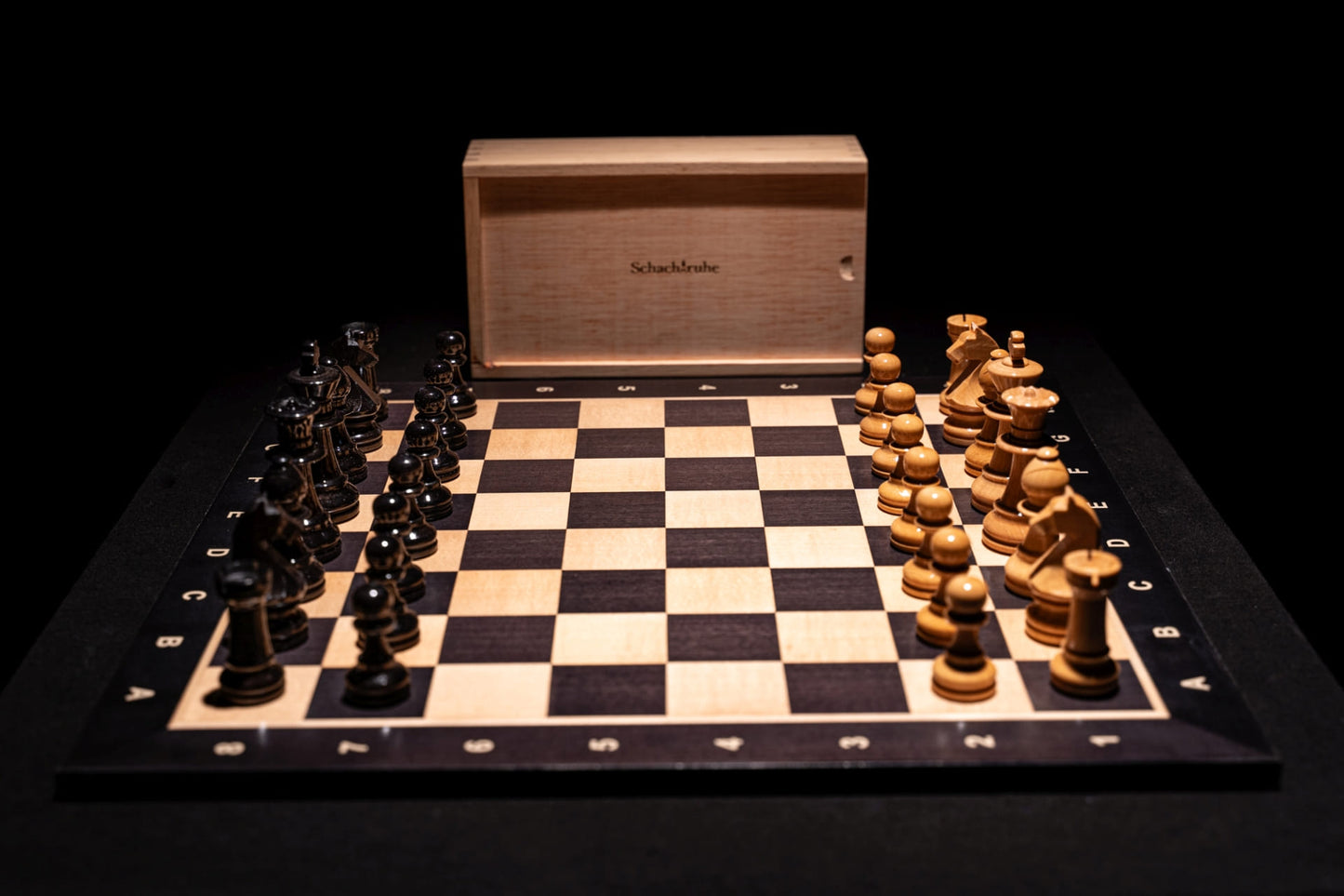 Aufgebautes Schachspiel Zilata in glänzend mit Aufbewahrungstruhe im Hintergrund