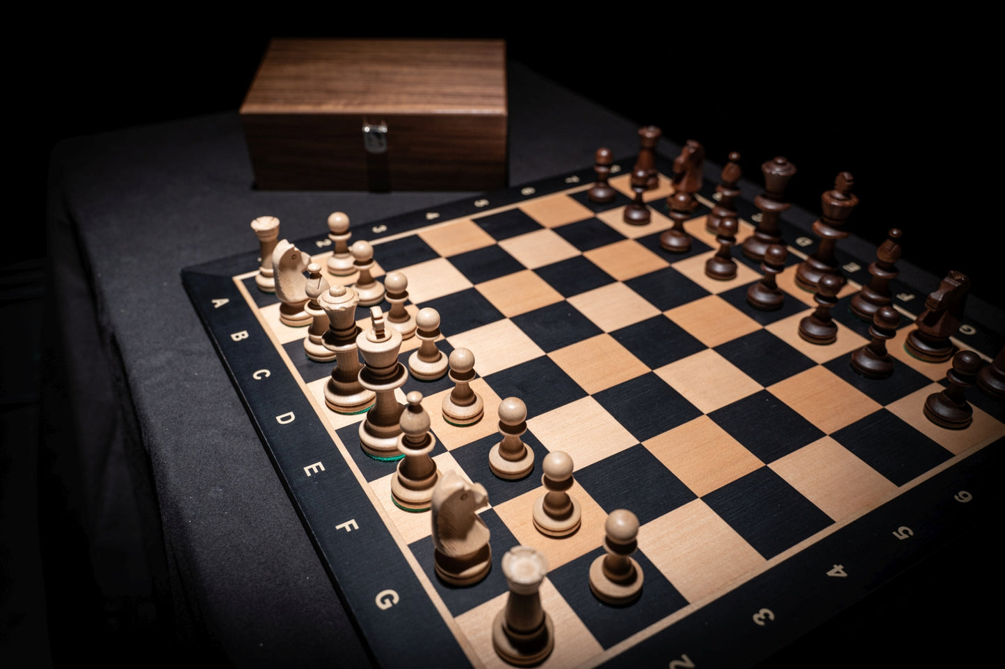Aufgebautes Schachspiel Calinea mit Aufbewahrungstruhe im Hintergrund