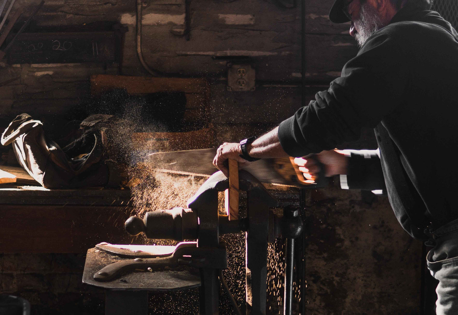 Mann der in einer Werkstatt Holz mit Handsäge sägt und dabei jede Menge Späne verursacht