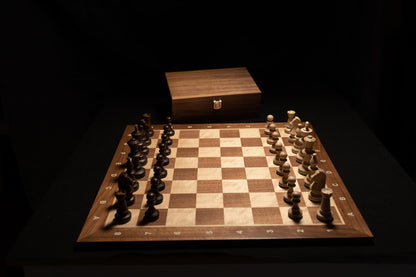 Schachbrett Bentam mit Figuren und Holztruhe im Hintergrund