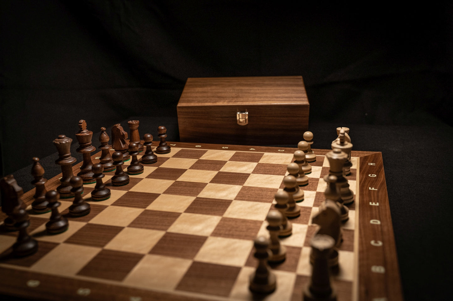 Aufgebautes Schachspiel Heramis mit Aufbewahrungstruhe im Hintergrund