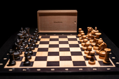 Aufgebautes Schachspiel Zilata in matt mit Aufbewahrungstruhe im Hintergrund
