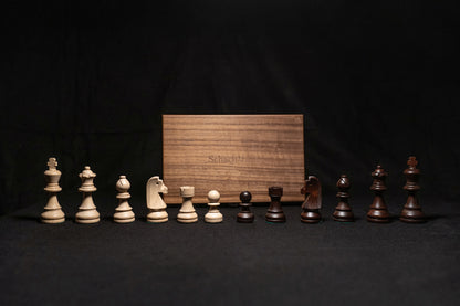 Figurensatz des Schachspiels Manatos aufgereiht mit Aufbewahrungstruhe im Hintergrund