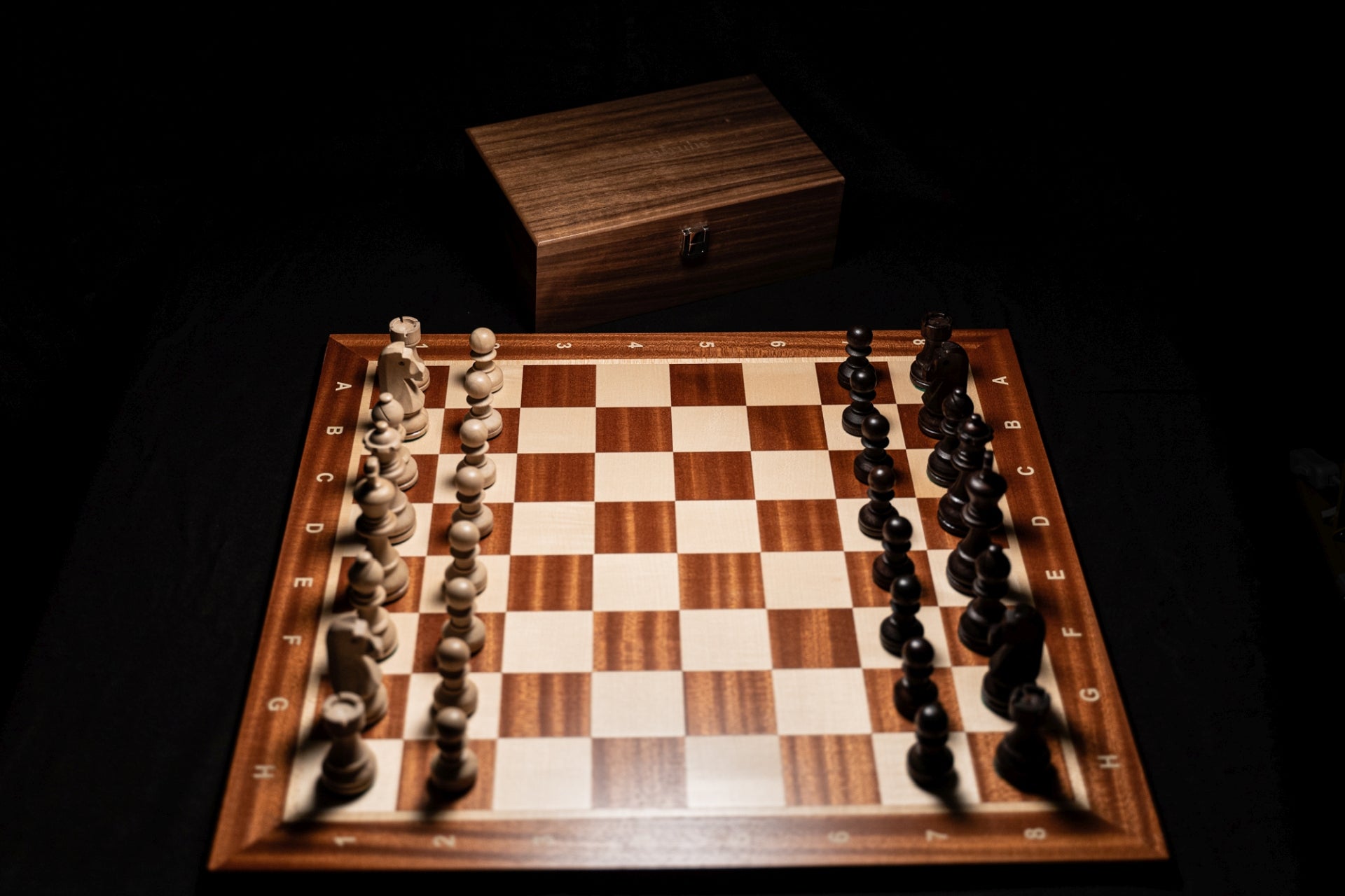 Schachbrett Rokko mit Figuren und Holztruhe im Hintergrund