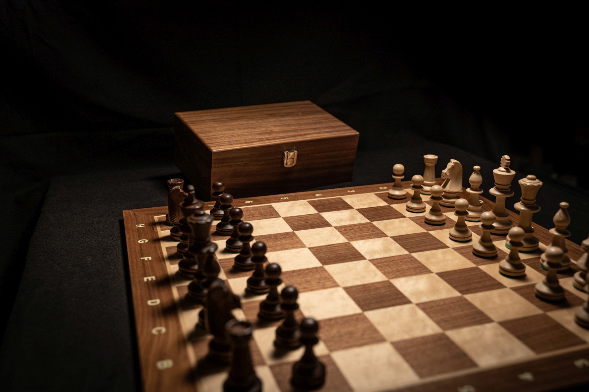 Aufgebautes Schachspiel Heramis mit Aufbewahrungstruhe im Hintergrund